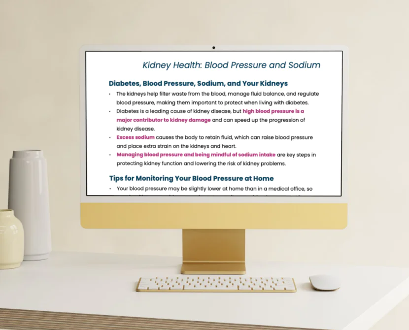 A gold and white desktop computer displays an article titled Kidney Health: Blood Pressure, Sodium, and Meals with diabetes tips. The computer sits on a white desk with a keyboard, mouse, and two vases in the background.