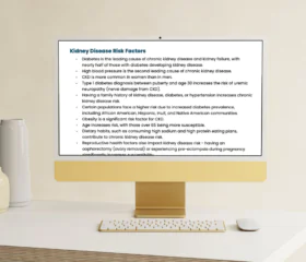 A computer monitor on a beige desk displays text about kidney disease risk factors, listing causes such as diabetes, high blood pressure, and family history. A white keyboard and mouse are on the desk.