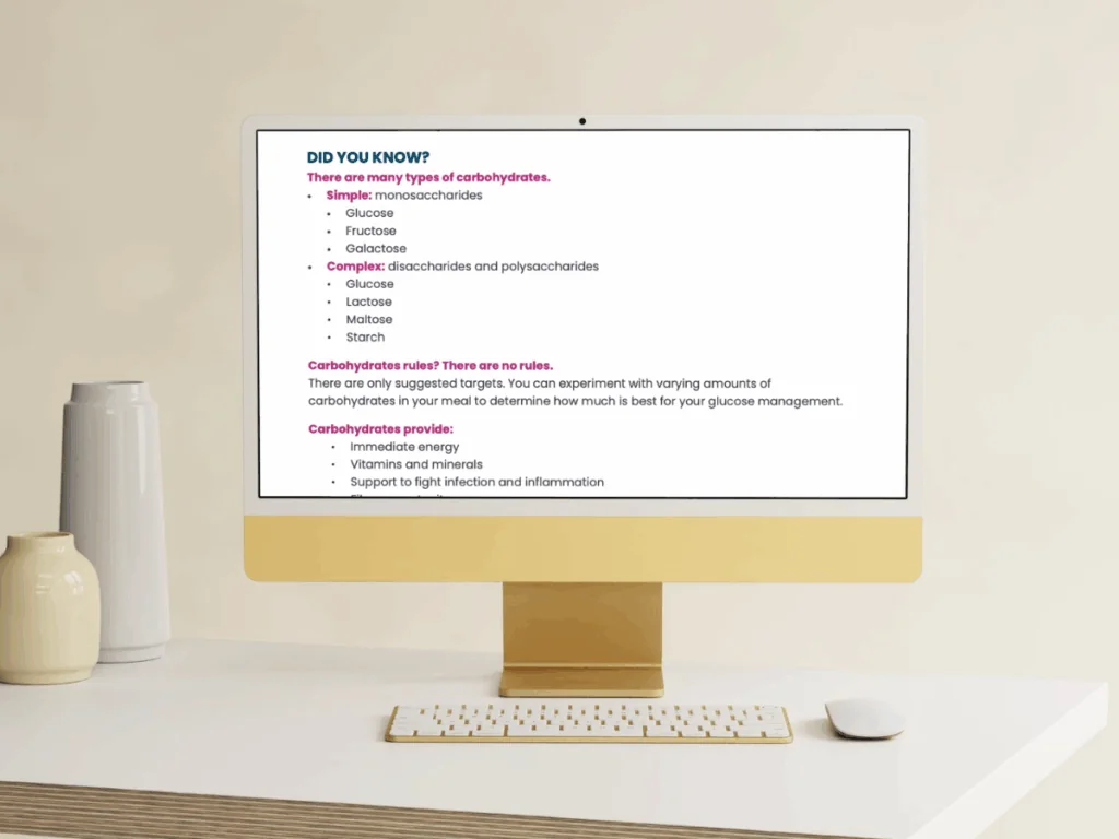 A modern desktop computer on a beige desk displays text about types of carbohydrates. The screen lists simple and complex carbohydrates and mentions that there are no strict carbohydrate rules. A blurred chair and vase are in the background.