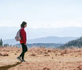 A woman walking outdoors in the mountains, breathing deeply in the fresh air, symbolizing lightness and freedom in diabetes management.