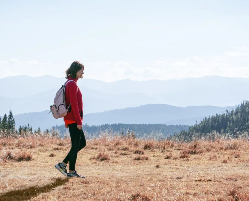 A woman walking outdoors in the mountains, breathing deeply in the fresh air, symbolizing lightness and freedom in diabetes management.